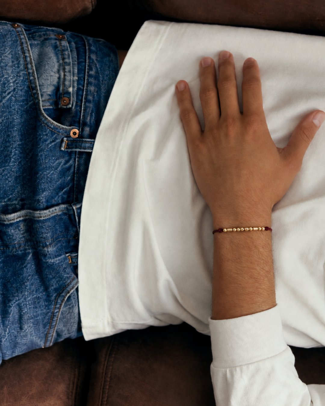 Une main posée sur un oreiller, le bracelet au poignet